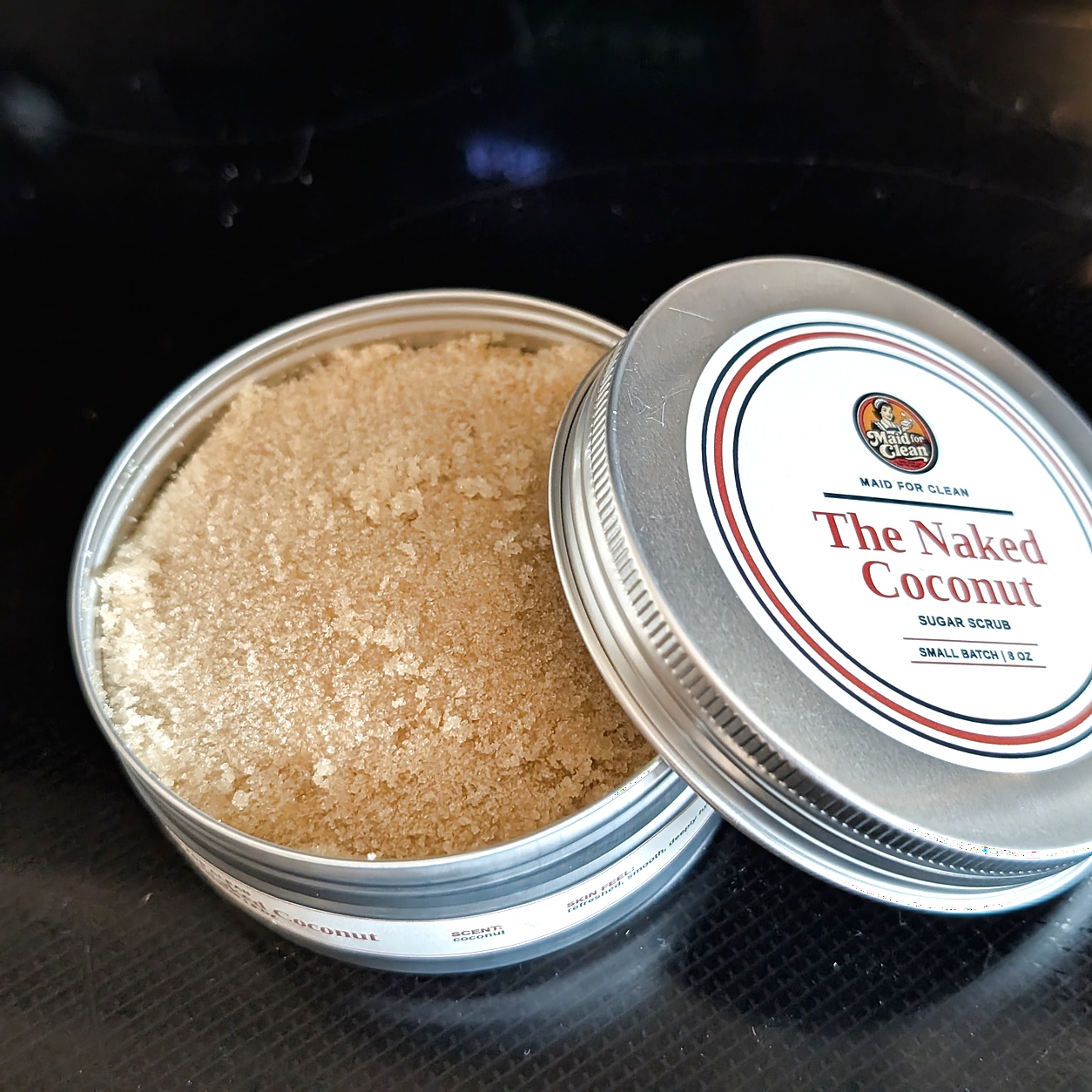 Open Naked Coconut sugar scrub tin with labeled lid